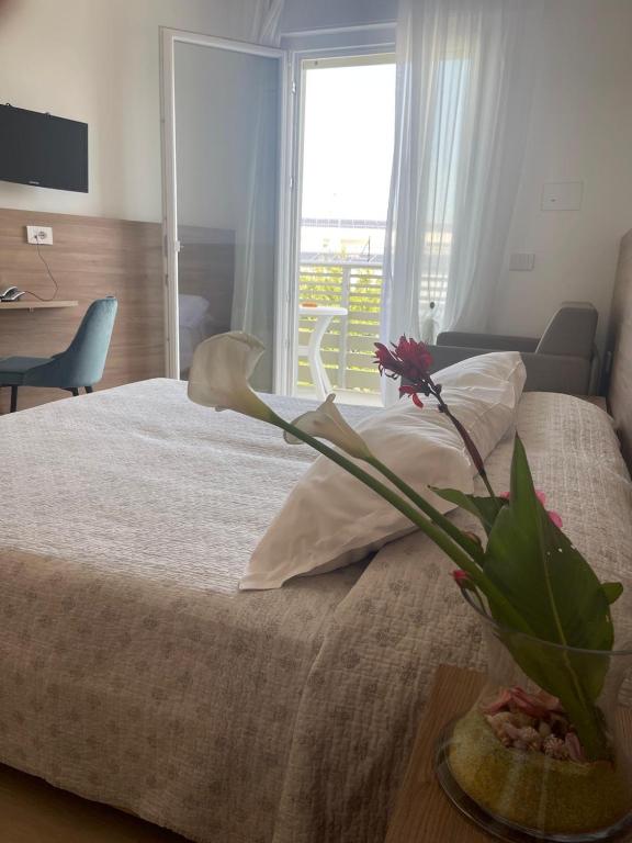 a bedroom with a bed with a vase of flowers on it at Hotel Berna in Eraclea Mare