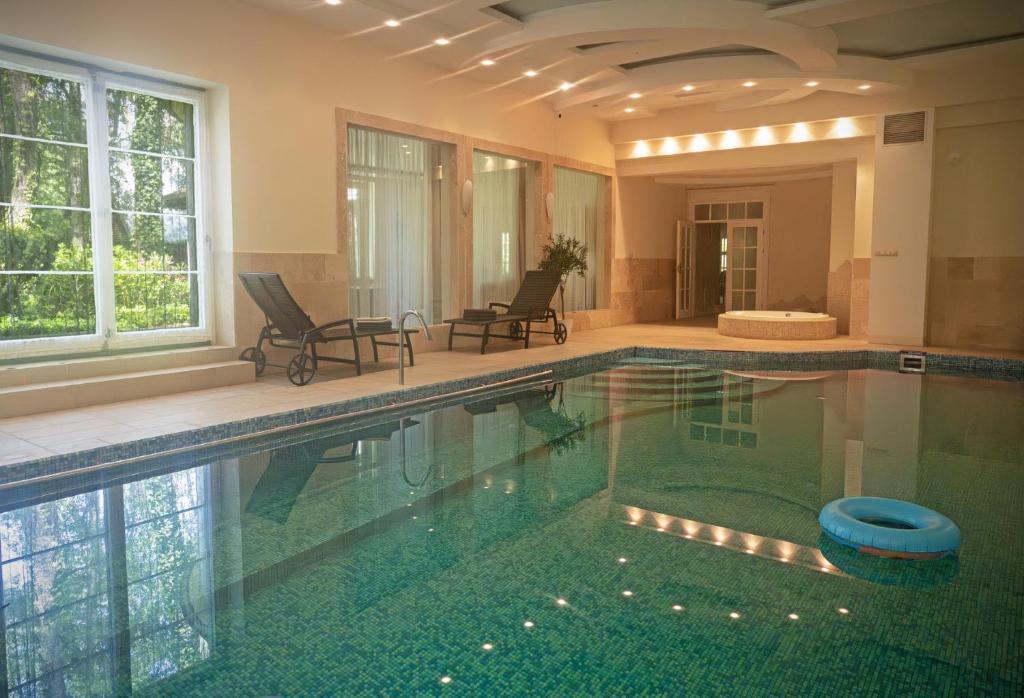 a swimming pool in a house with two chairs at Luxury villa indoor pool Warsaw in Magdalenka