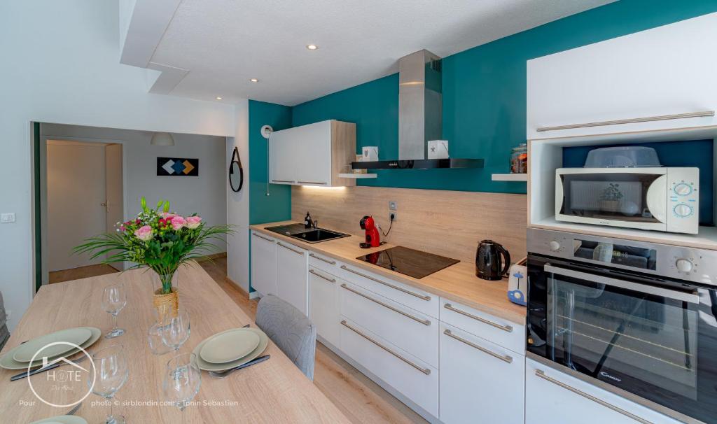 a kitchen with blue walls and a table with flowers at Sérénité près du Lac in Aix-les-Bains