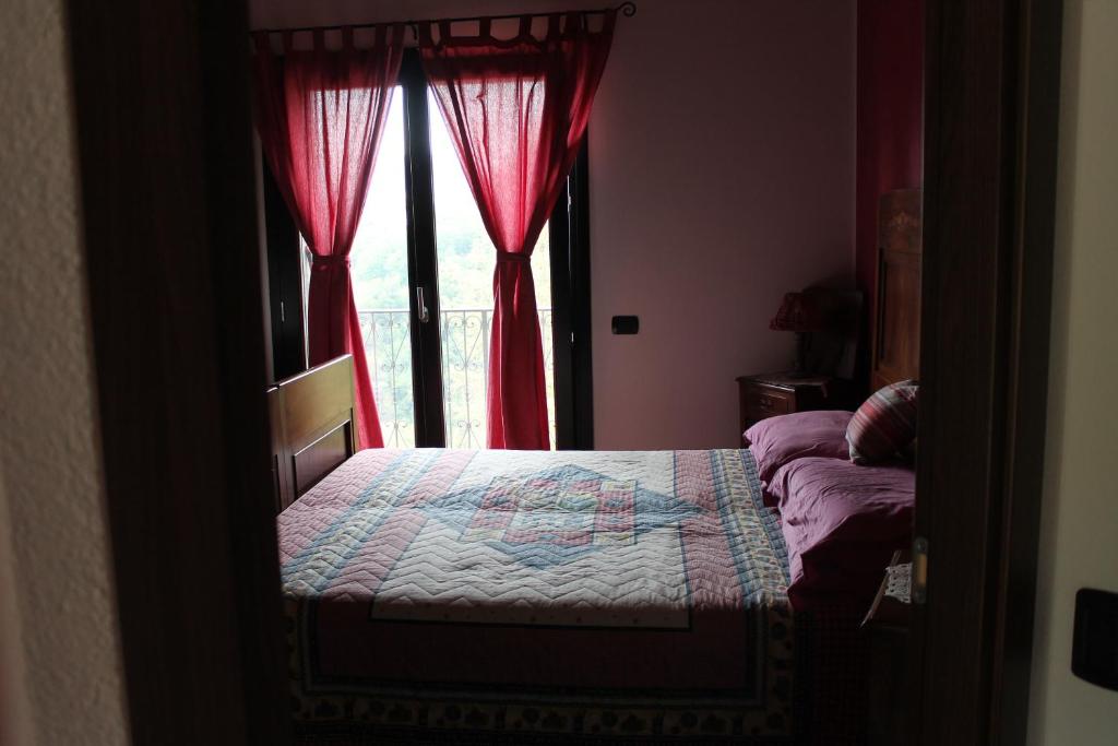 a bedroom with a bed and a window with red curtains at Baita del bosco in Laino