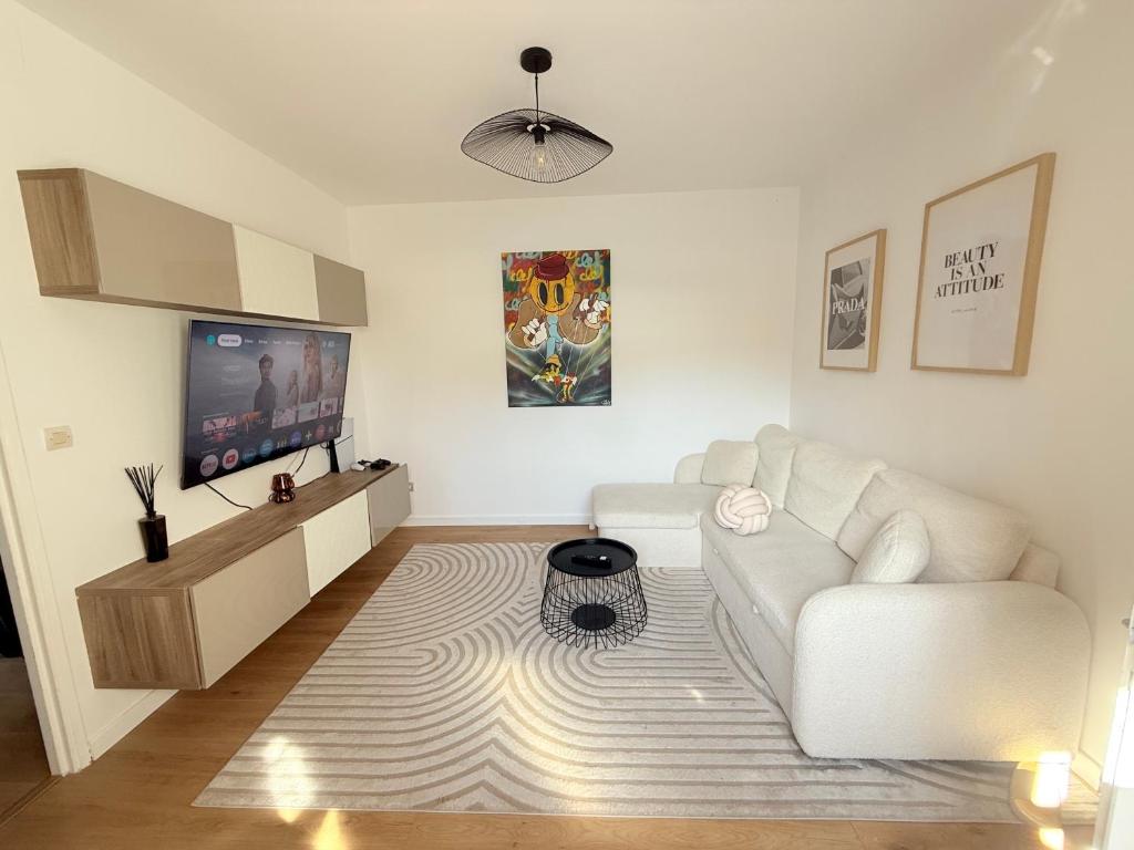 Il comprend un salon doté d'un canapé blanc et d'une télévision à écran plat. dans l'établissement Charmante Maison indépendante T3, à Suresnes