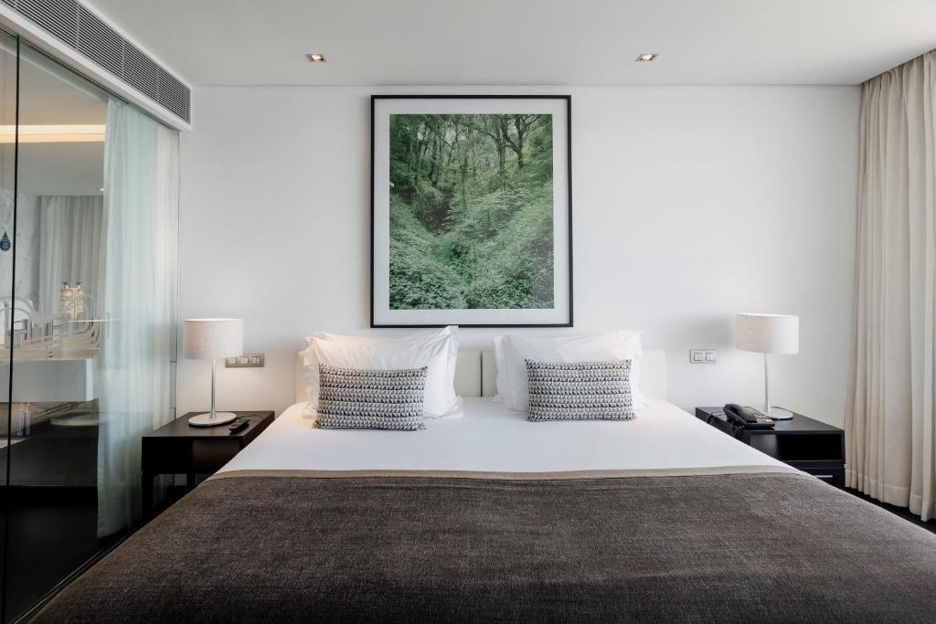 a bedroom with a large white bed with two lamps at Troia Design Hotel in Troia