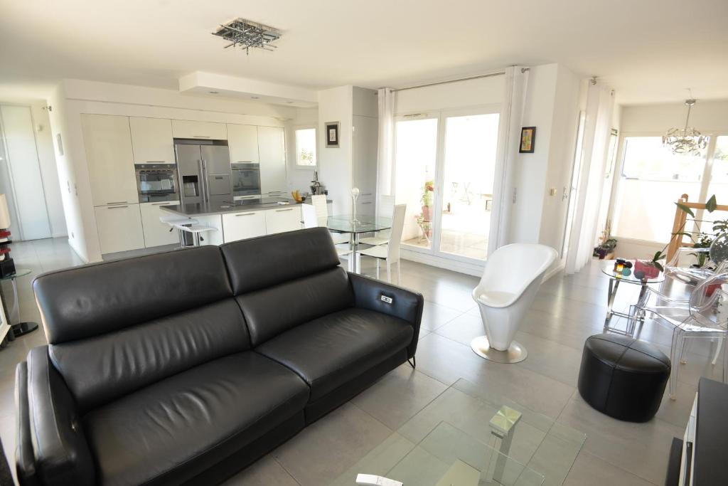 un salon avec un canapé noir et une cuisine dans l'établissement Luxueux Duplex avec Jacuzzi, 2 chambres, 2 Lits, à Castelnau-le-Lez