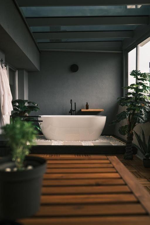 a bathroom with a large tub and potted plants at Ikigai Penthouse Apartment in Banja Luka