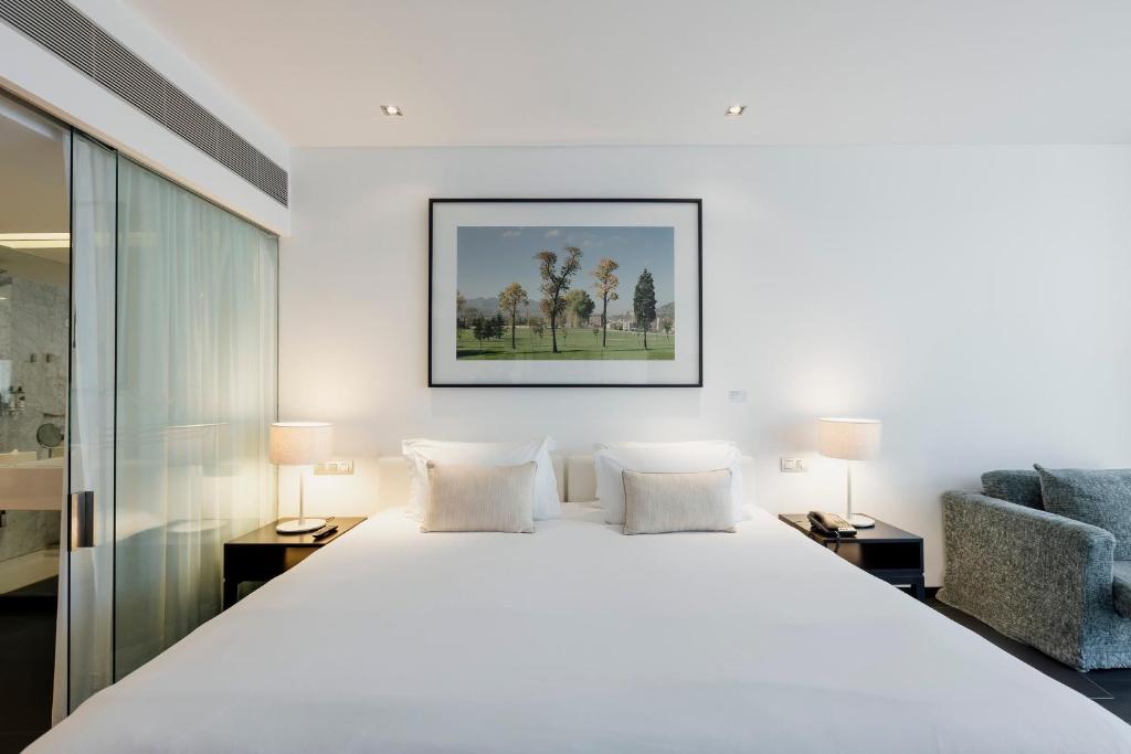 a bedroom with a large white bed and a chair at Troia Design Hotel in Troia