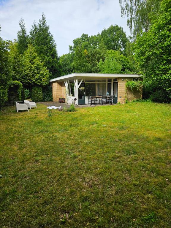 a small house in the middle of a yard at Bungalow Eekhoorn | 4 personen - Vakantiepark De Kremmer in Gasselte