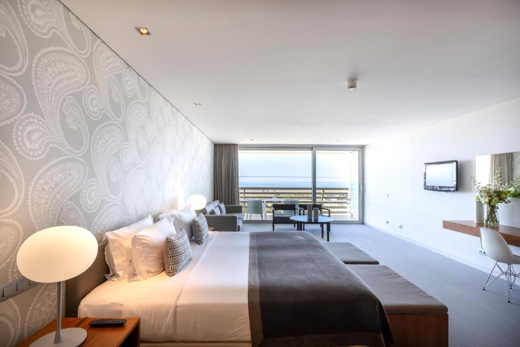 a bedroom with a large bed and a living room at Troia Design Hotel in Troia