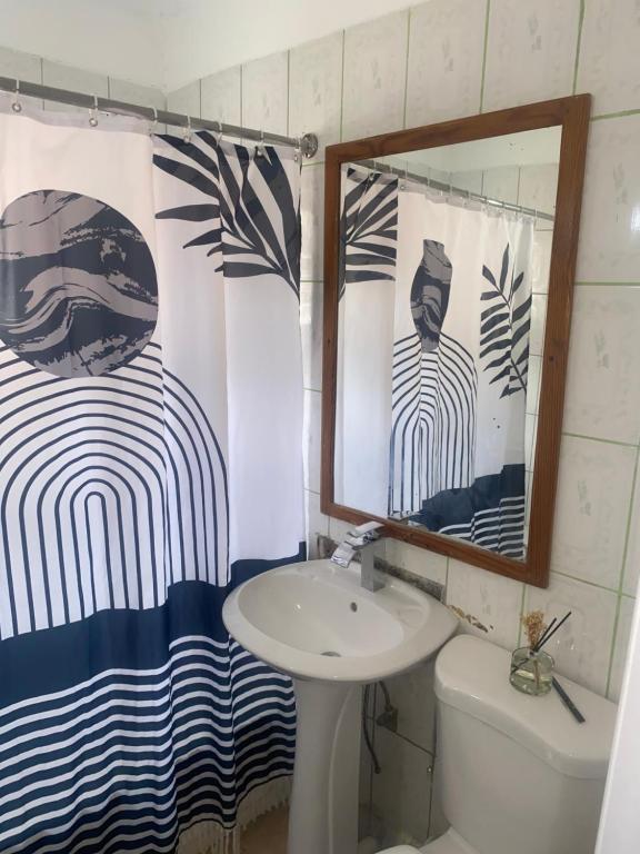 a bathroom with a sink and a toilet and a shower curtain at Golden Nest in Port Antonio