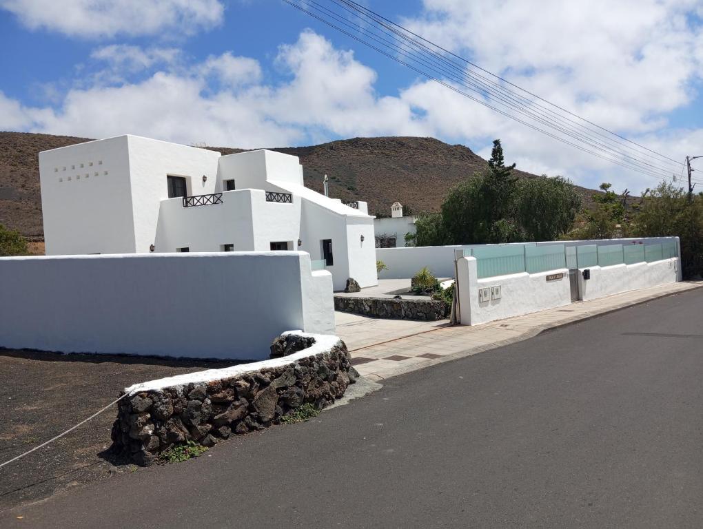 a white building on the side of a road at Finca la Tabaiba piscina compartida adultos in Máguez