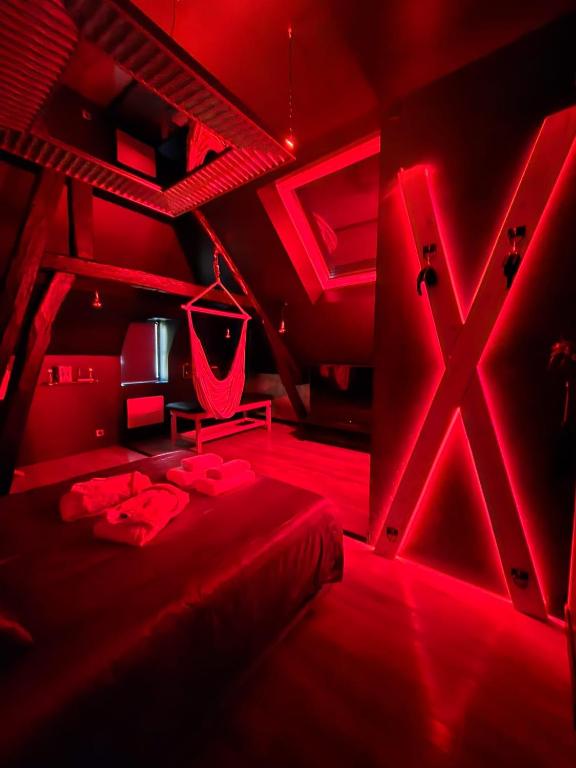 une chambre rouge avec un lit et un panneau de hache dans l'établissement L'instant love, à Verneuil-sur-Avre