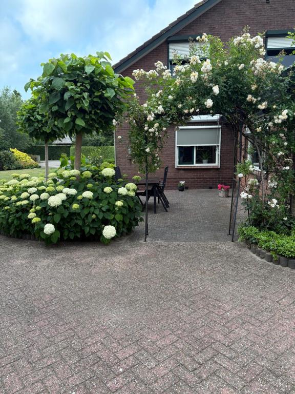 a garden with roses and a bench in front of a building at Vakantiehuisje Wekerom in Wekerom