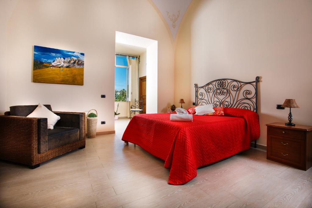a bedroom with a bed with a red blanket and a chair at Relais Il Pennino in Massa Lubrense