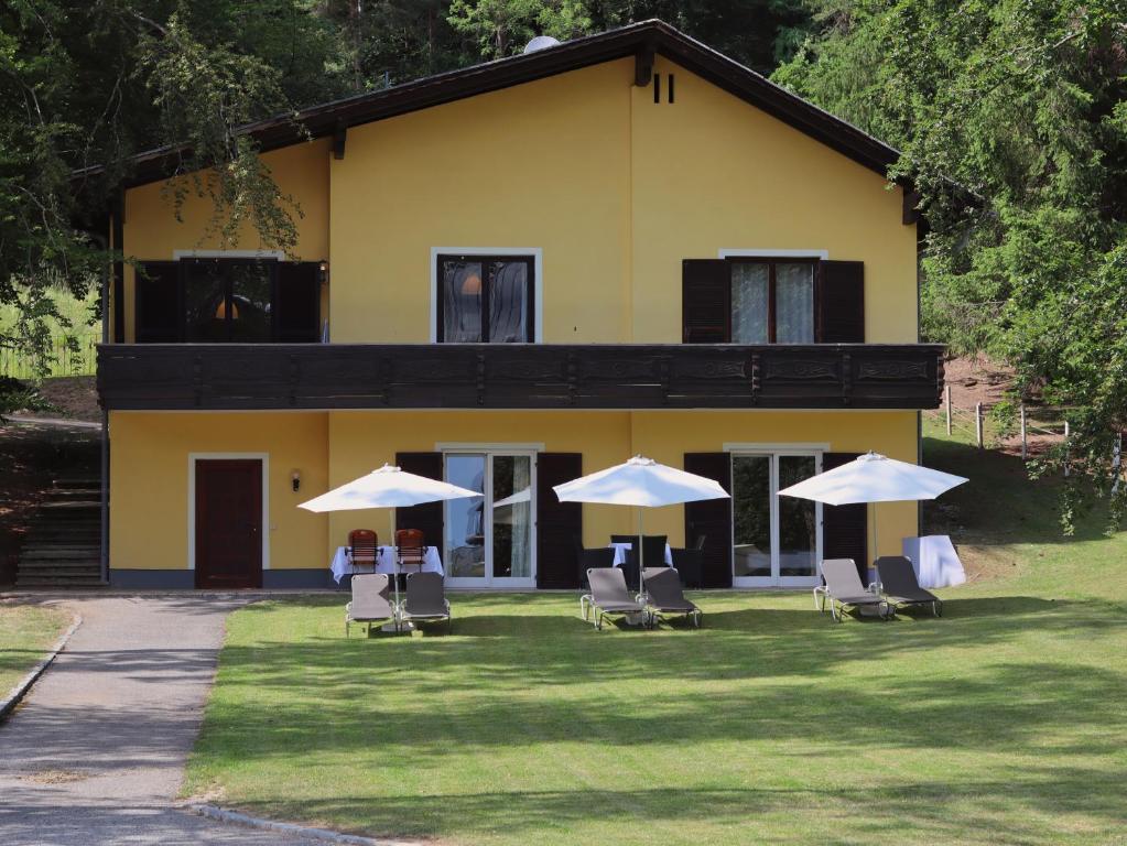 a yellow house with chairs and umbrellas in front of it at Haus im Park in Sankt Kanzian