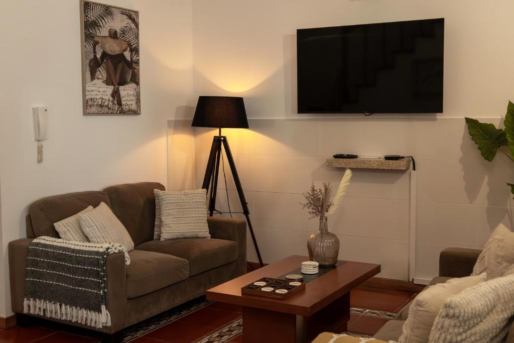 a living room with a couch and a tv on a wall at Casa Borda da Rocha in Nordeste