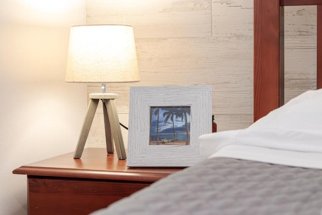 a lamp on a table with a picture on a bed at Casa Borda da Rocha in Nordeste