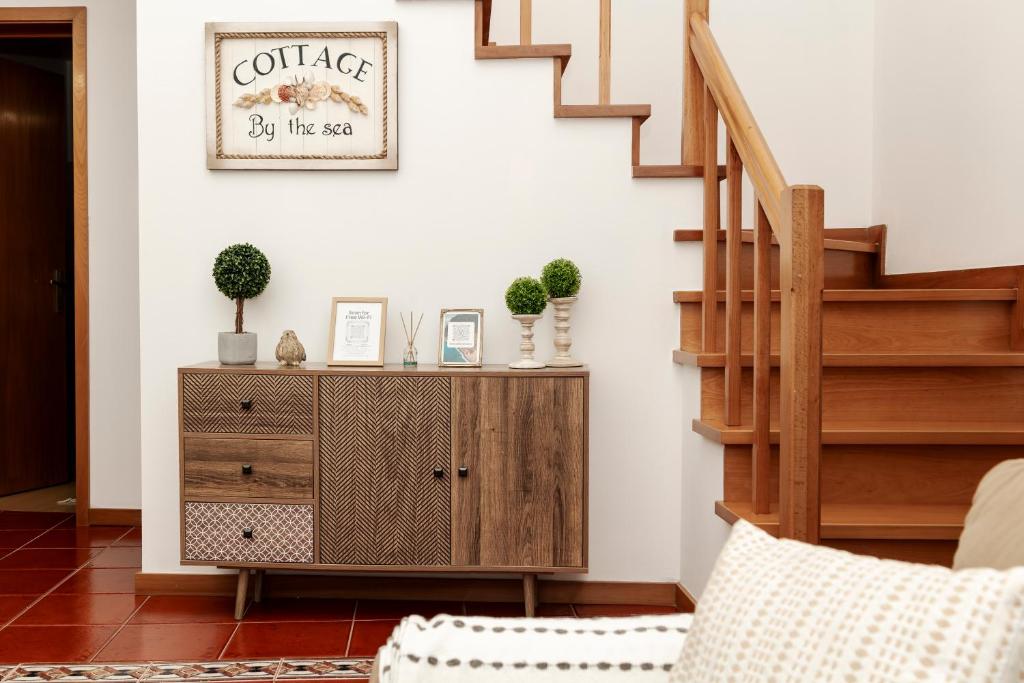 a living room with a wooden cabinet and stairs at Casa Borda da Rocha in Nordeste