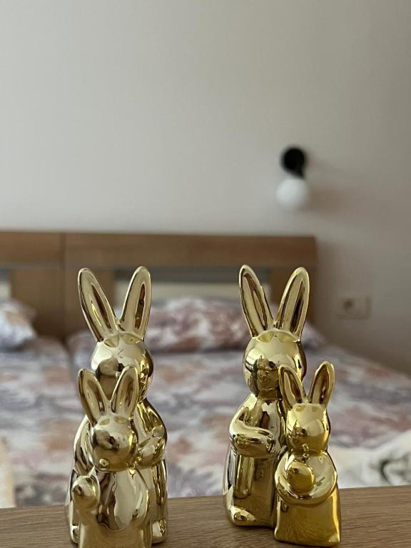 two gold rabbits sitting on a table in front of a bed at Apartman Park in Skopje