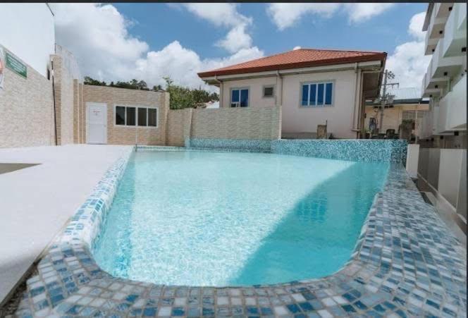 a swimming pool with blue water in front of a house at Cebu stay-Thyme residences in Minglanilla