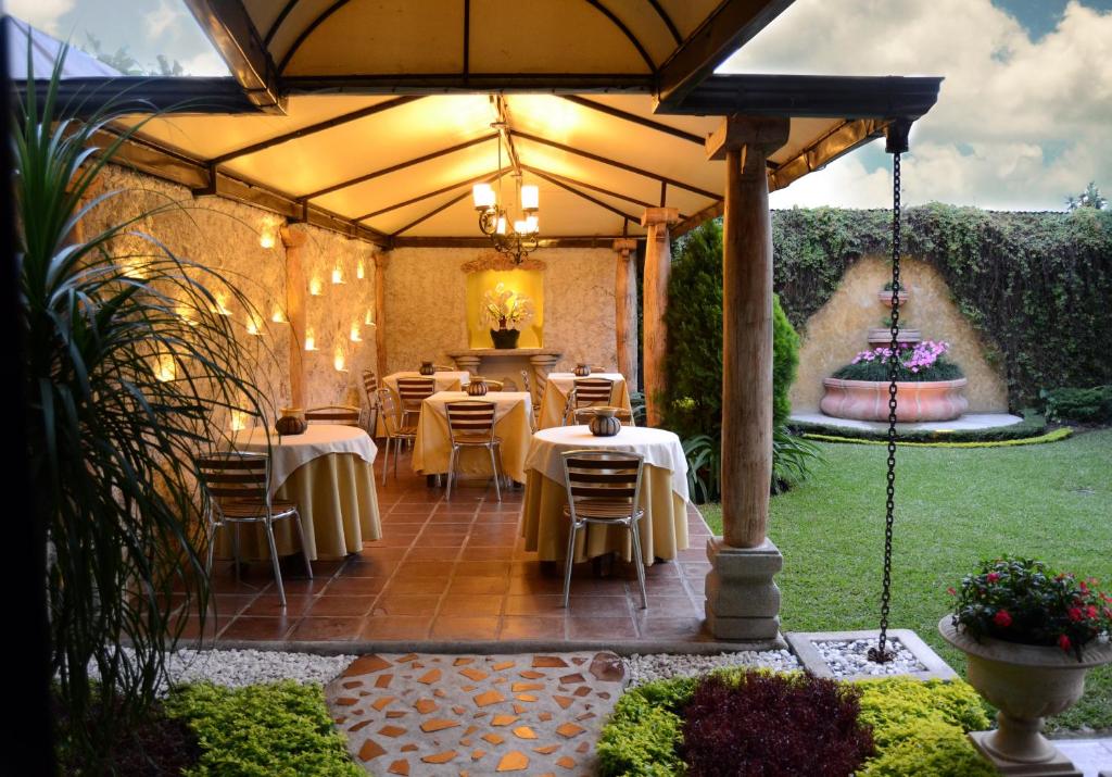 a patio with tables and chairs under a large umbrella at Hostal Villa Toscana in Guatemala