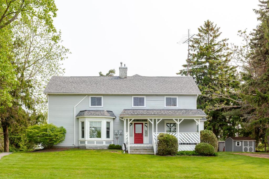una casa blanca con una puerta roja en un patio en Westlake Cottages - Highway House, en Wellington