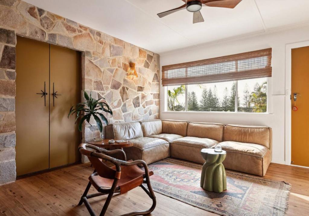 a living room with a couch and a stone wall at Sundowner Suite No. 2 in Yamba