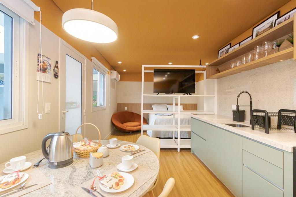 a kitchen and living room with a table with food on it at Studio Opera de Arame 01 Vaga em Estacionamento in Curitiba