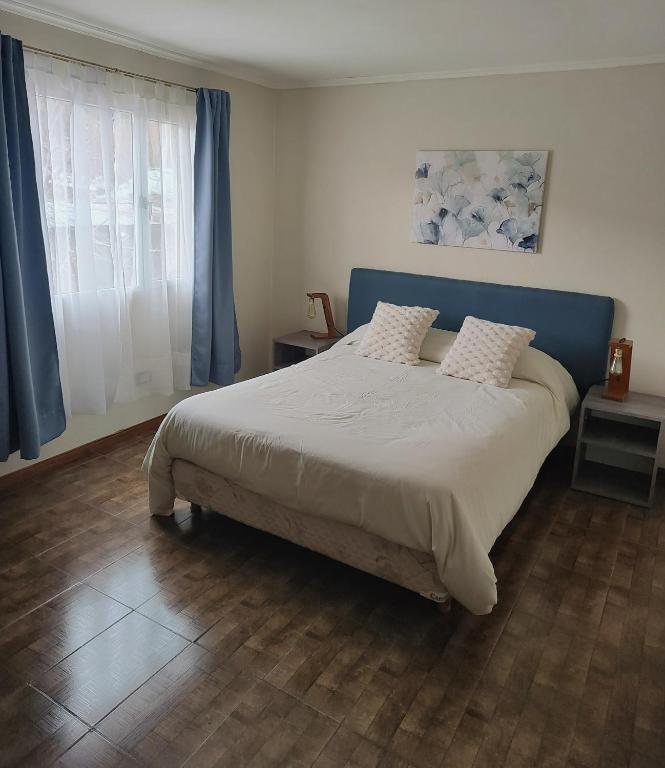 a bedroom with a large bed with a blue headboard at Alojamiento El Cóndor in Esquel