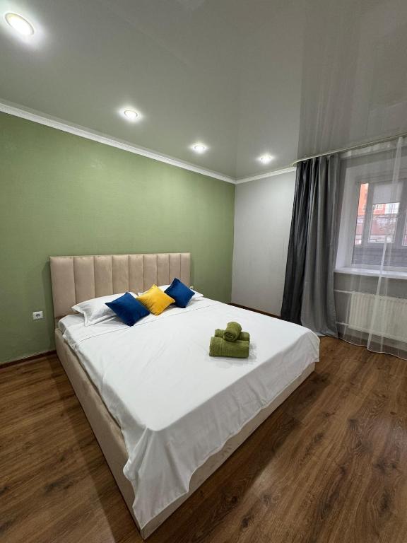a bedroom with a large white bed with blue and yellow pillows at Tkacheva 14 in Pavlodar