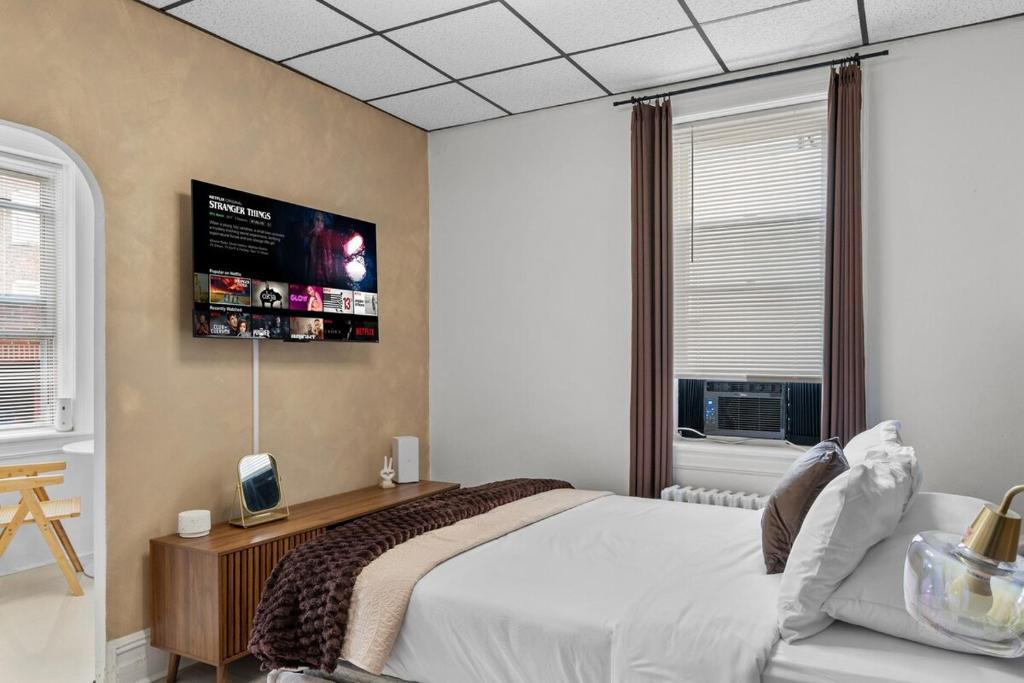 a bedroom with a bed and a flat screen tv at Modern Studio - Parking Available - 15 min NYC in Jersey City