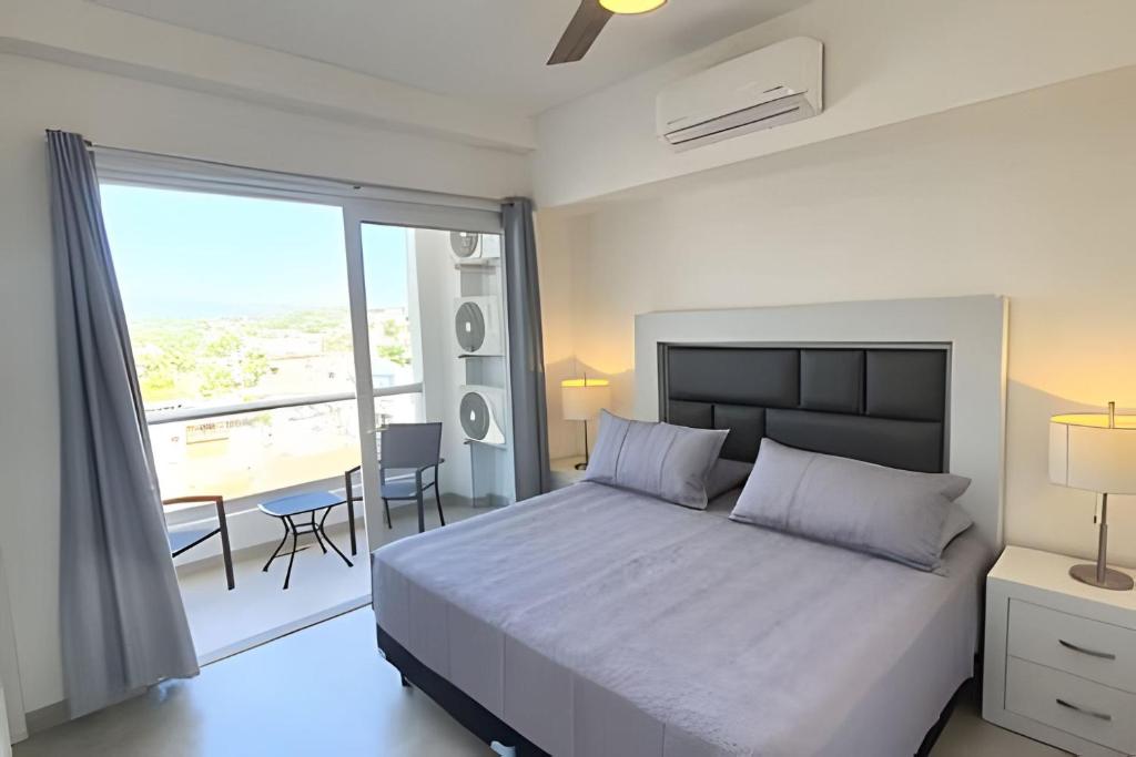Un dormitorio con una cama y un balcón con una mesa. en Costa Paraíso D-20 2-Recamaras, en Bucerías