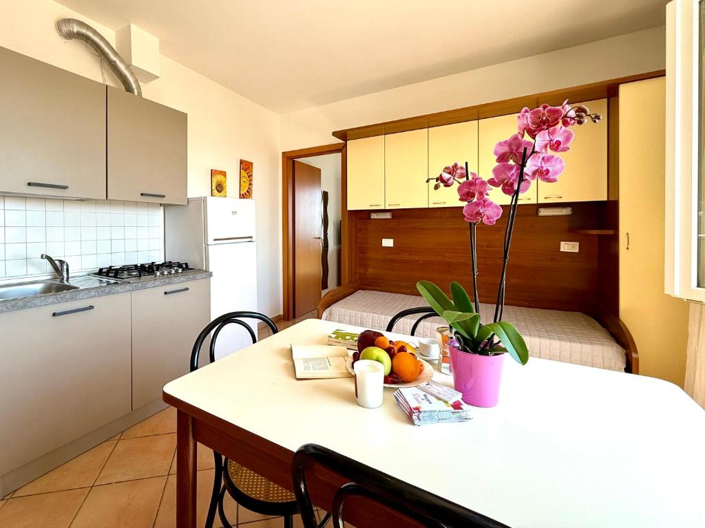 a kitchen with a table with a vase of flowers on it at Residence Carioca in Rimini