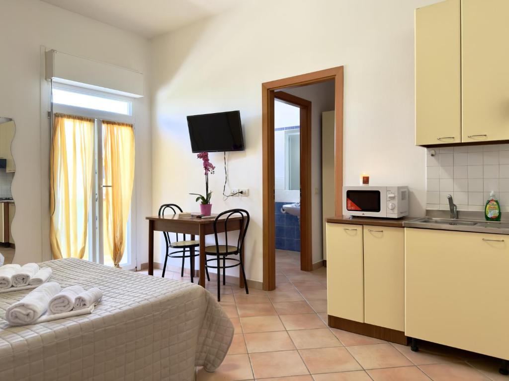a room with a bed and a kitchen and a table at Residence Carioca in Rimini
