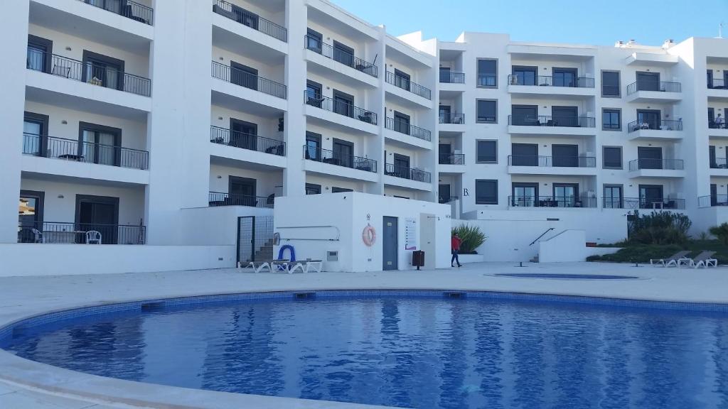 アルブフェイラにあるVista das Ondas Apartamento 205 B2 - Olhos de Aguaのアパートメントの建物の前にスイミングプールがあります。