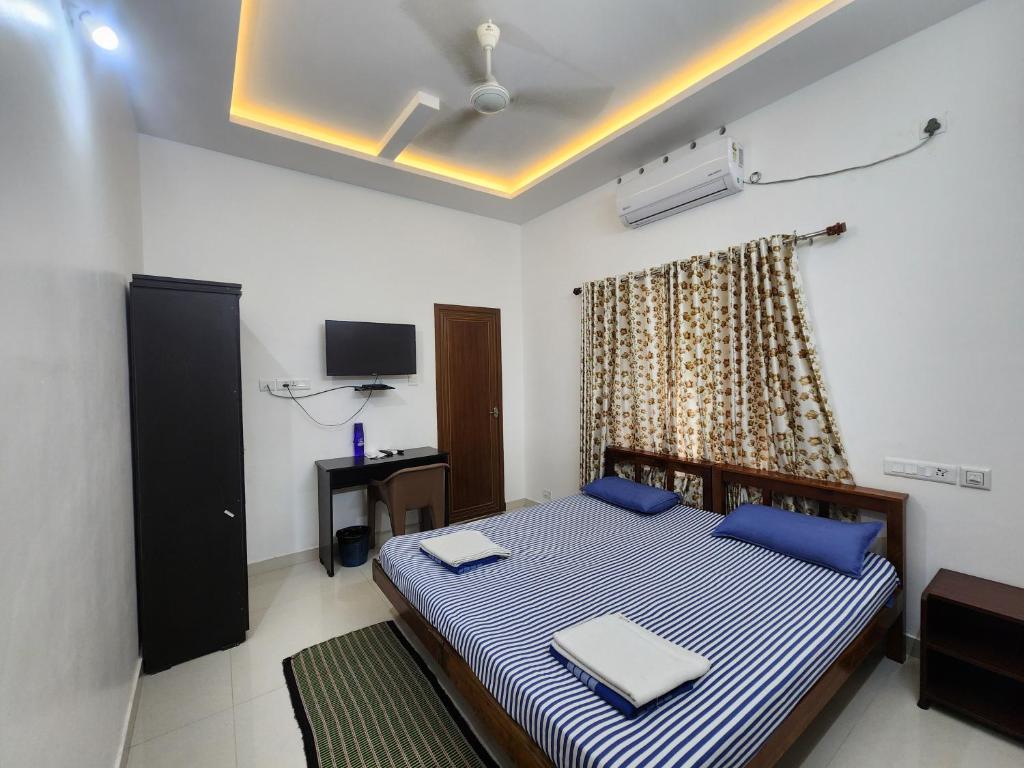 a bedroom with a bed with blue pillows at Happyhomes Homestay Trivandrum in Trivandrum