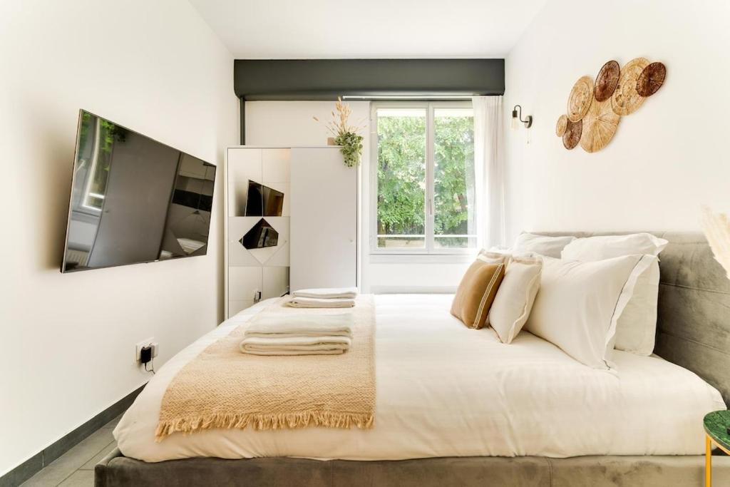 1 dormitorio blanco con 1 cama grande con almohadas blancas en Rez de jardin relaxant et calme, en Neuilly-sur-Seine