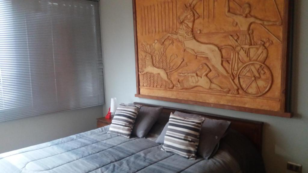 1 dormitorio con 1 cama con una pintura en la pared en Apartop, en Santiago