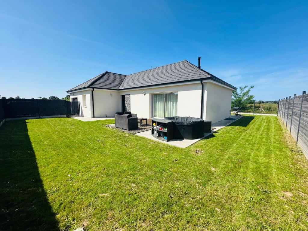 une petite maison blanche avec une cour gazonnée dans l'établissement Maison de charme en bord de mer avec jacuzzi, à Merville-Franceville-Plage