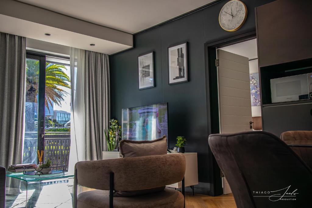 a living room with a chair and a clock on the wall at KML Nine Palms luxury 101 in Cape Town