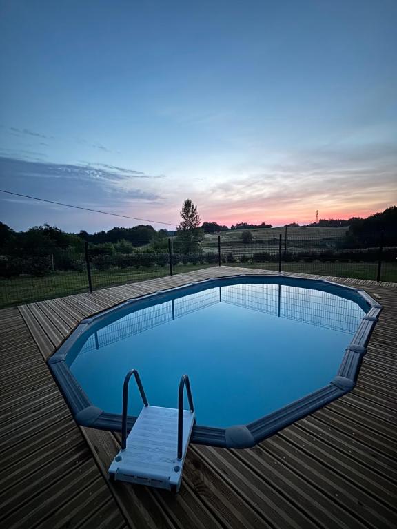 - une piscine sur une terrasse en bois avec une chaise à côté dans l'établissement Maison à la campagne avec piscine et jacuzzi, à Cadouin