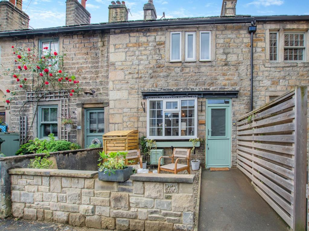 a brick house with a blue door and a fence at Duckling Cottage in Addingham