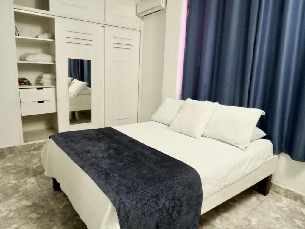 a bedroom with a white bed with blue curtains at Apartamento Edificio calima in San Andrés