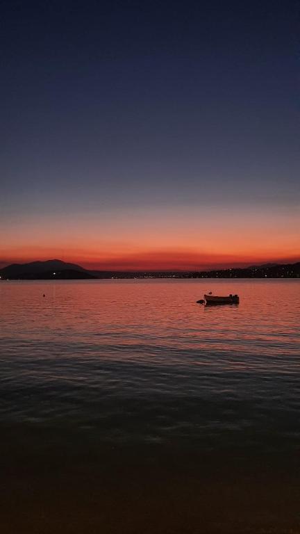 a boat in the middle of the water at sunset at Galazio suites 2 Seaside in Salamina