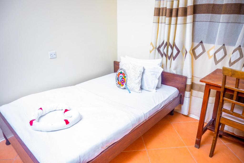 Un dormitorio con una cama con sábanas blancas y una mesa. en Malkiya house, en Zanzíbar
