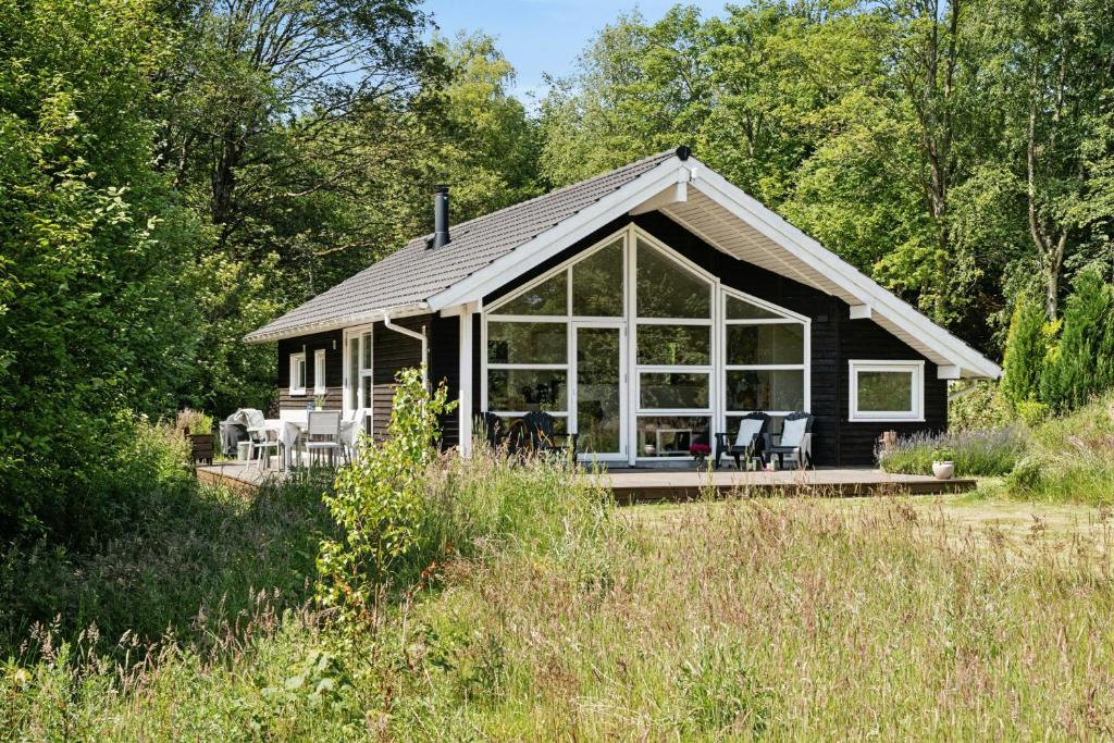 HøjslevにあるSkovhus Med Bæk Ved Hjarbæk Fjordの大きなガラス窓のある黒いコテージ