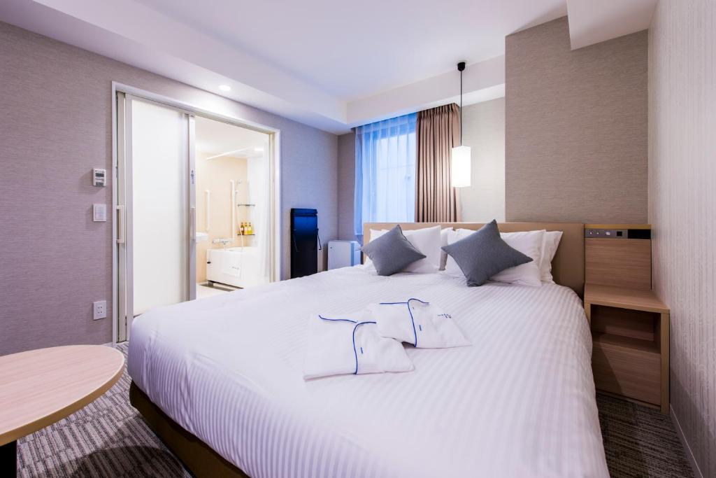 a bedroom with a large white bed with two pillows at Meitetsu Inn Hamamatsucho in Tokyo