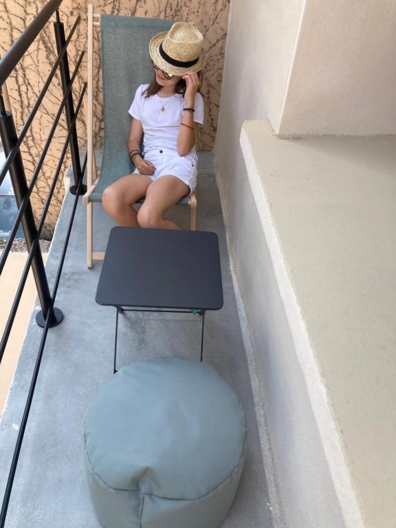 une jeune fille assise sur une chaise avec un chapeau dans l'établissement Résidence Thau t'M, à Mèze