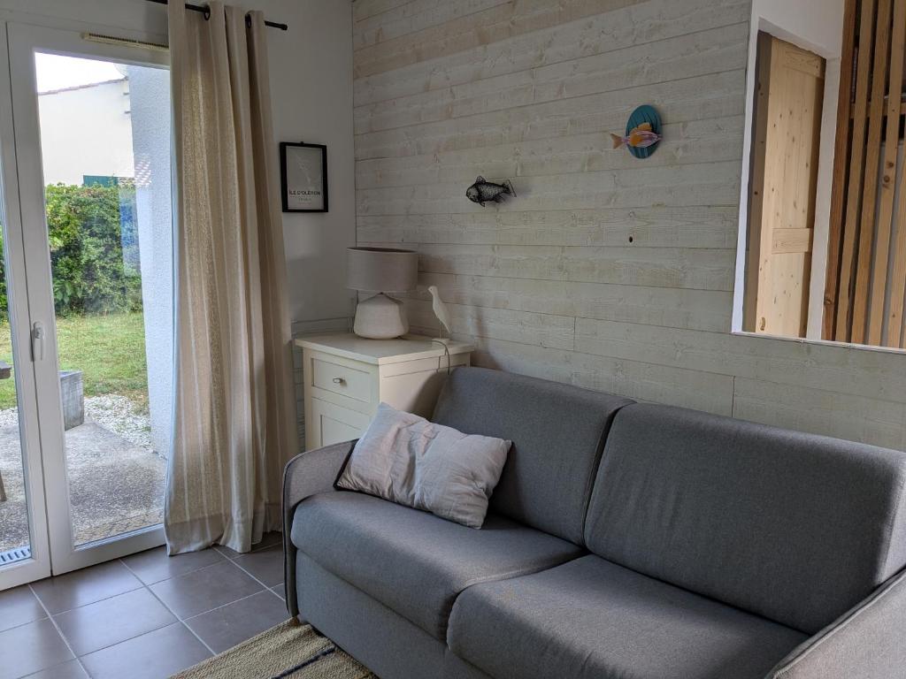 a couch sitting in a living room next to a door at Petite Maison Chaleureuse avec piscine in Dolus d'Oléron
