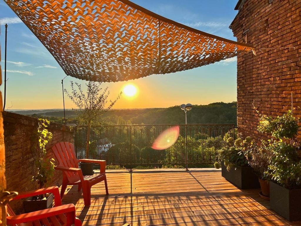 a deck with two chairs and the sunset in the background at Designer townhouse with 2 stunning terraces in Lafrançaise