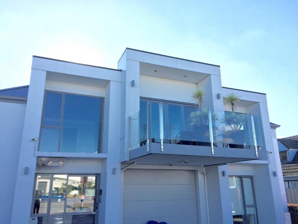 a white house with a balcony with palm trees on it at Alpha Motel in Christchurch