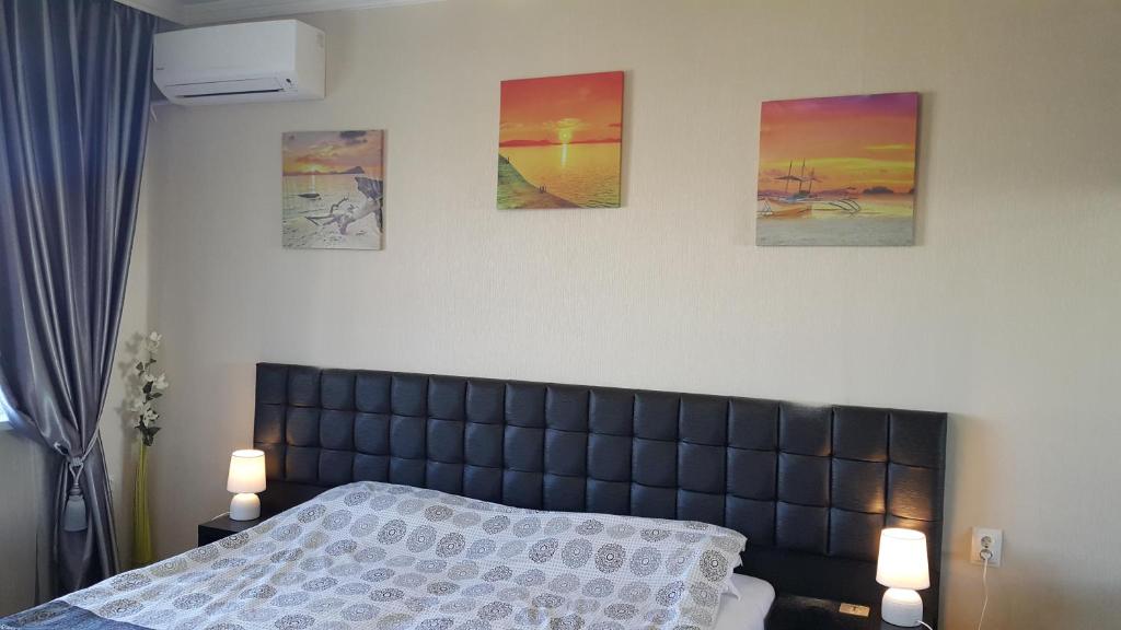 um quarto com uma cama com quatro fotografias na parede em Apartment Plamen Delux em Burgas